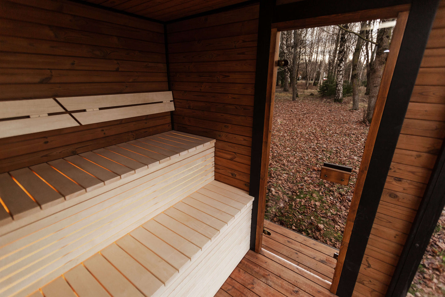 Sauna interior with wooden benches and outdoor forest view Mandespa USA. Modal Sauna. 