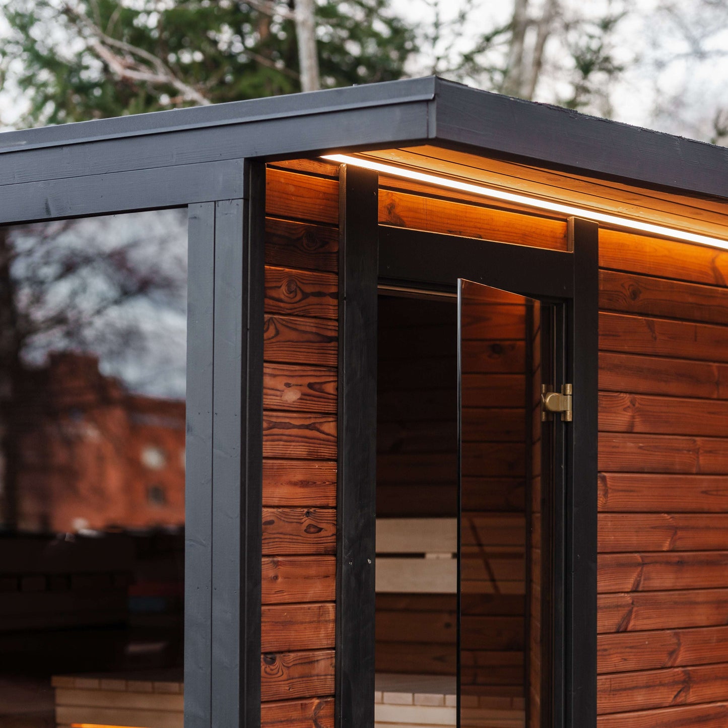 Sauna exterior with warm wood finish and black trim. Mandespa USA. Modal Sauna. 