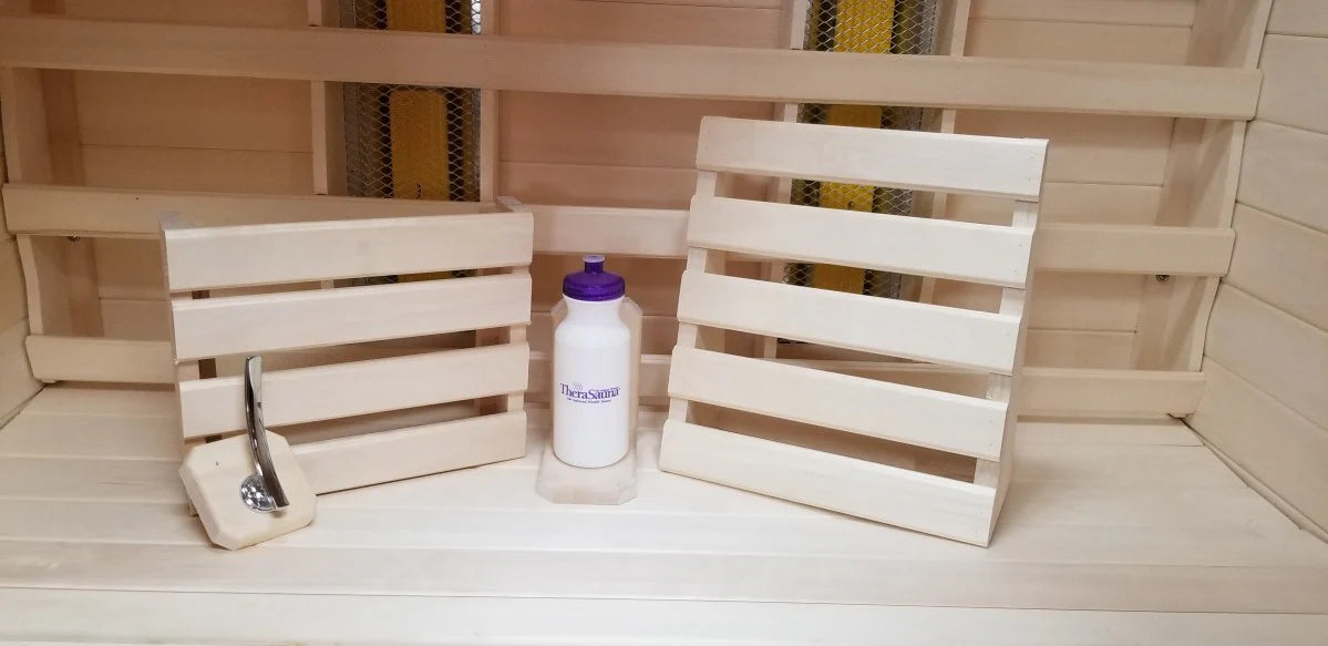 Wooden sauna with a bench, chair, brush, and bottle of water inside.